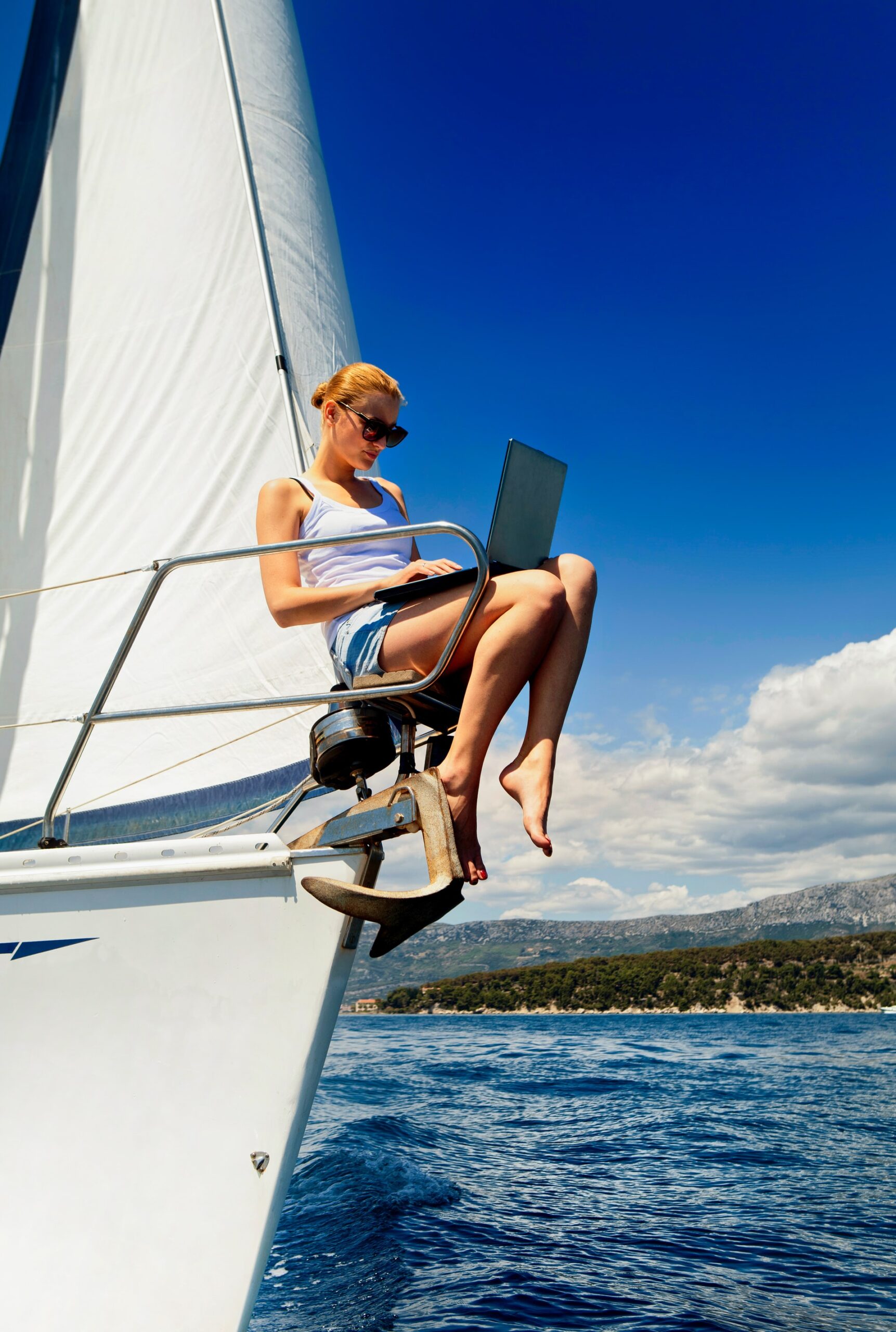 woman using laptop on bow of sailboat