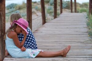 sad girls sitting on boardwalk at the beach